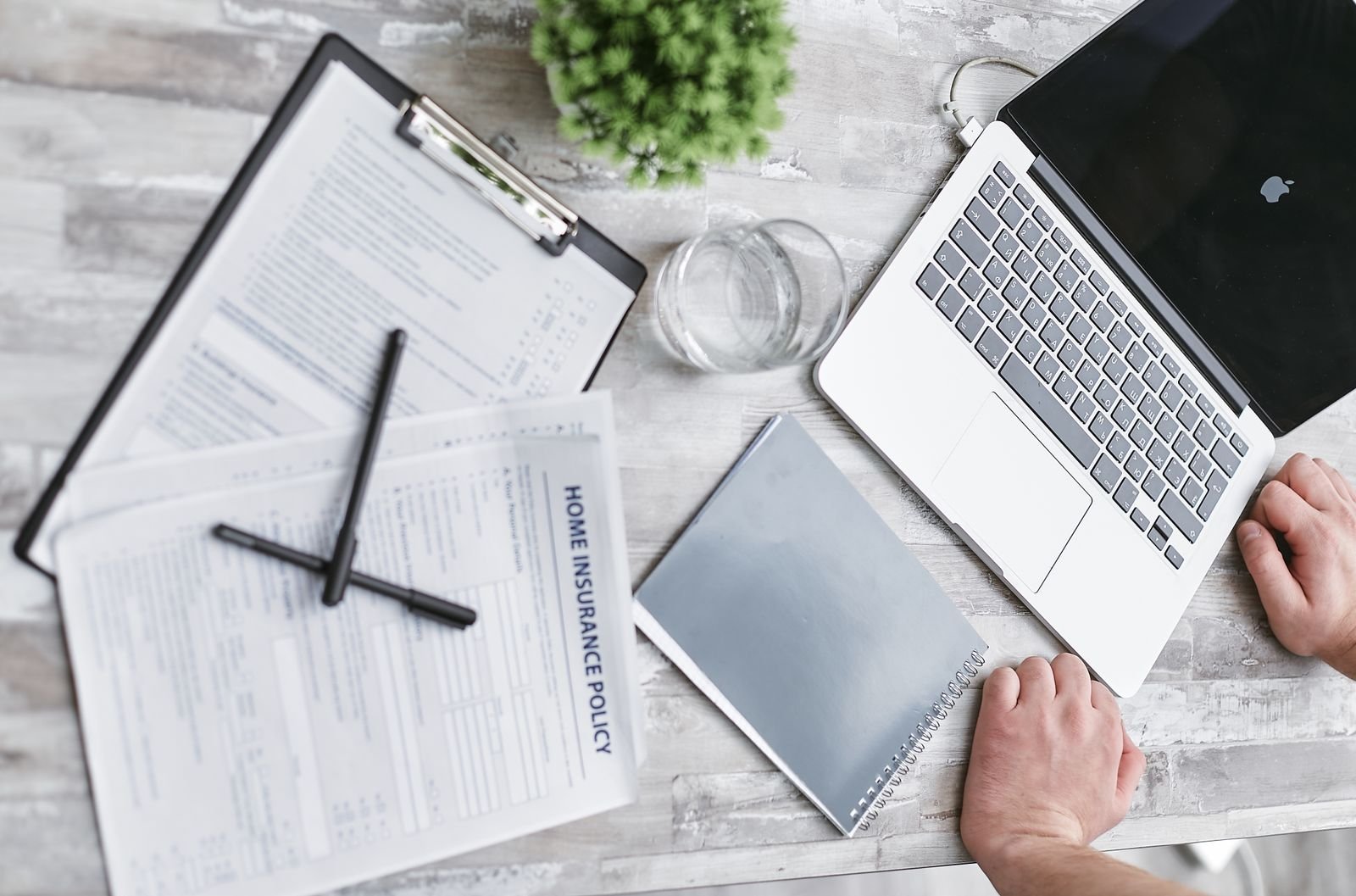 Insurance forms and a laptop on a desk used to check eligibility and authorization before claims are sent