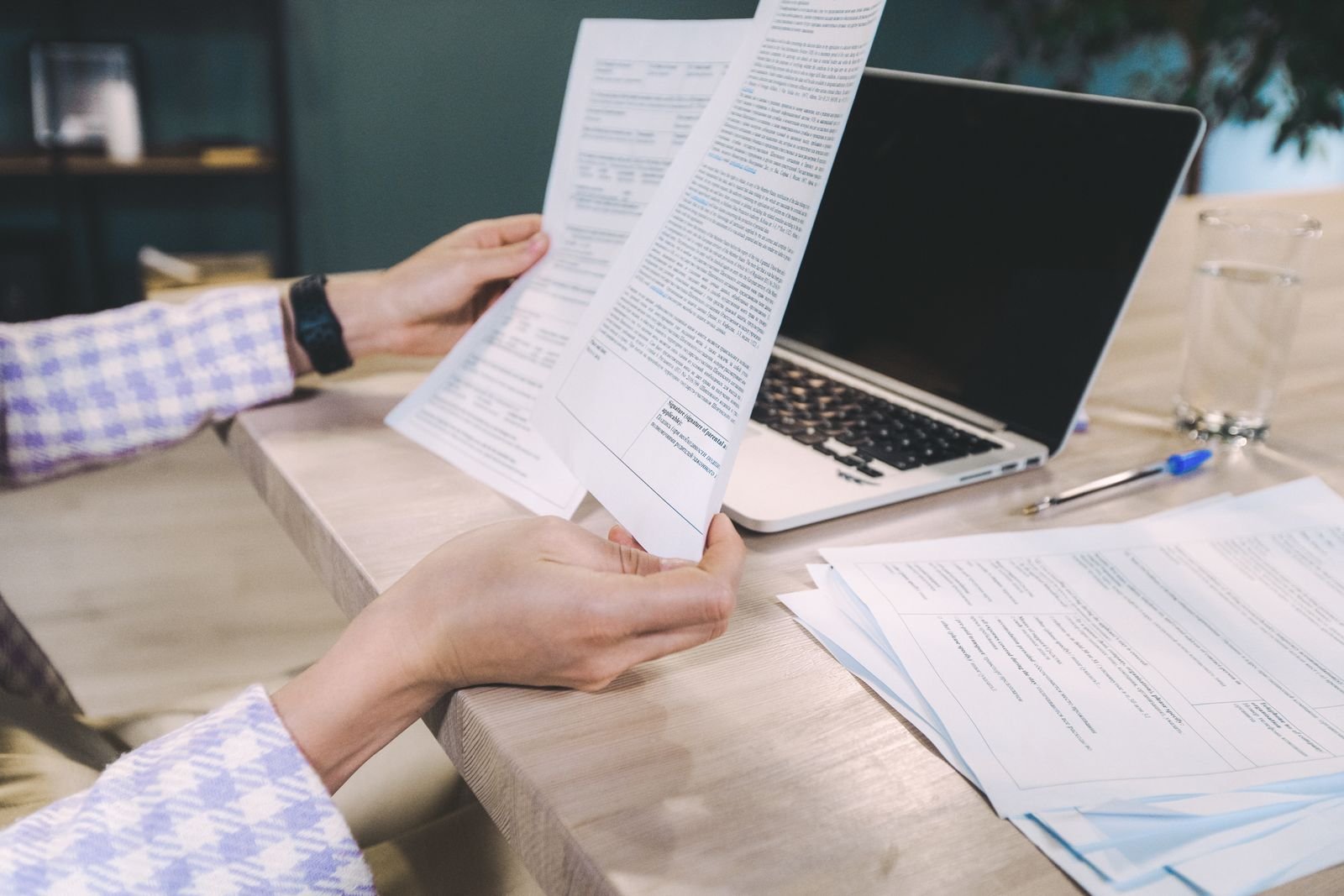 Hands reviewing printed claim documents next to a laptop during medical billing denial management